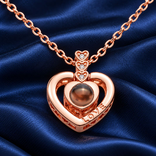 Roségoldfarbene Fotokette „Drei kleine Herzen“ von 4MyLove mit offenem LOVE-Herz und runder Fotolinse auf blauem Satin.