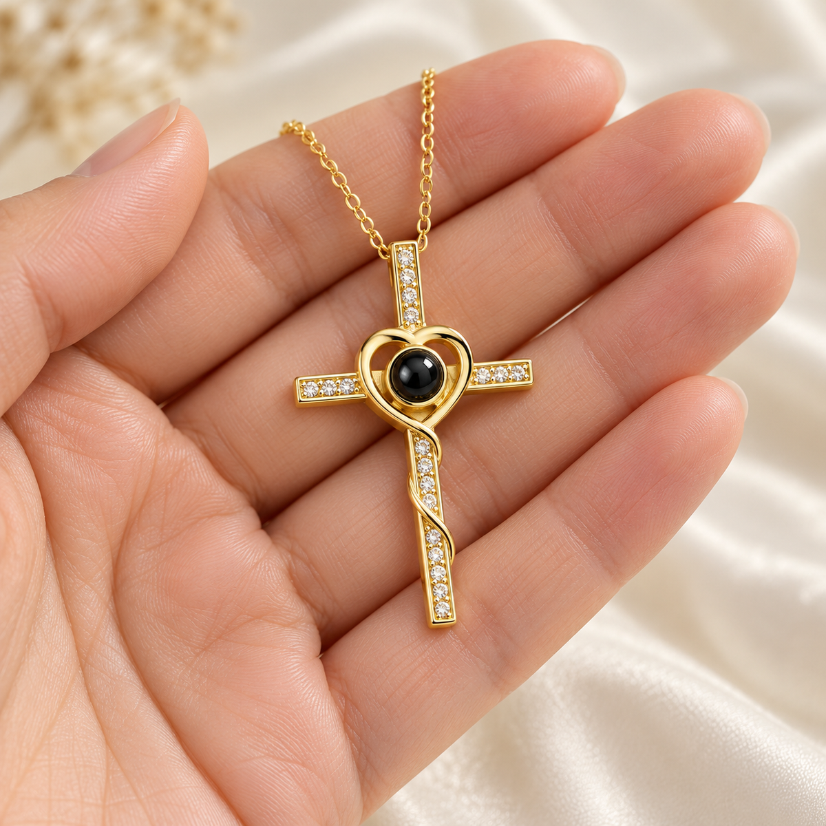 Goldene Kreuzkette mit Herz und Fotolinse in einer offenen Hand