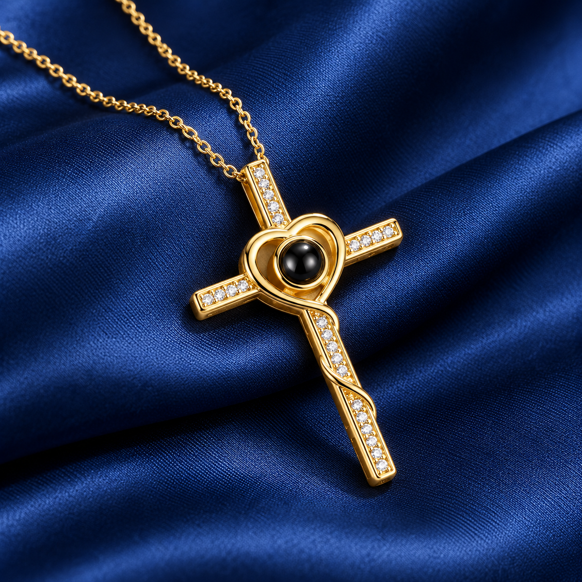 Goldene Fotokette mit Kreuz und Herz, kleinen Kristallen und schwarzer Projektionslinse auf dunkelblauem Satin