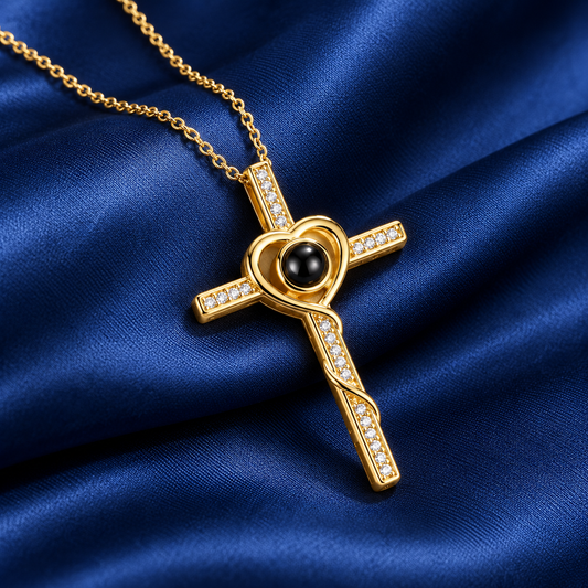 Goldene Fotokette mit Kreuz und Herz, kleinen Kristallen und schwarzer Projektionslinse auf dunkelblauem Satin
