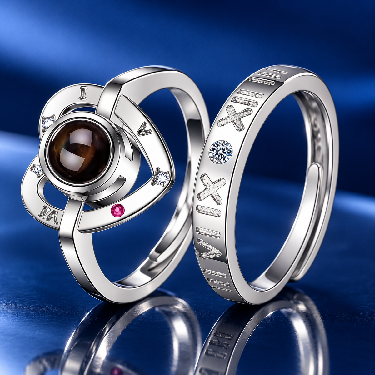 Silberne Partnerringe mit Herzlinse und römischen Ziffern vor blauem Satin