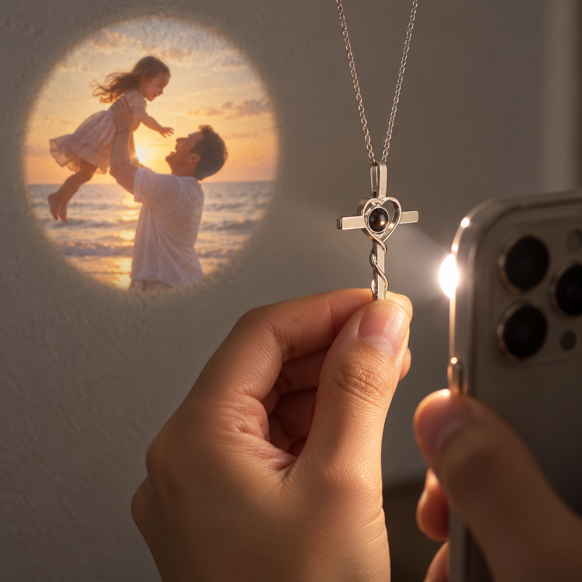 Kreuzanhänger mit Herz wird mit der Handy-Taschenlampe angeleuchtet und projiziert ein Familienfoto am Strand an die Wand