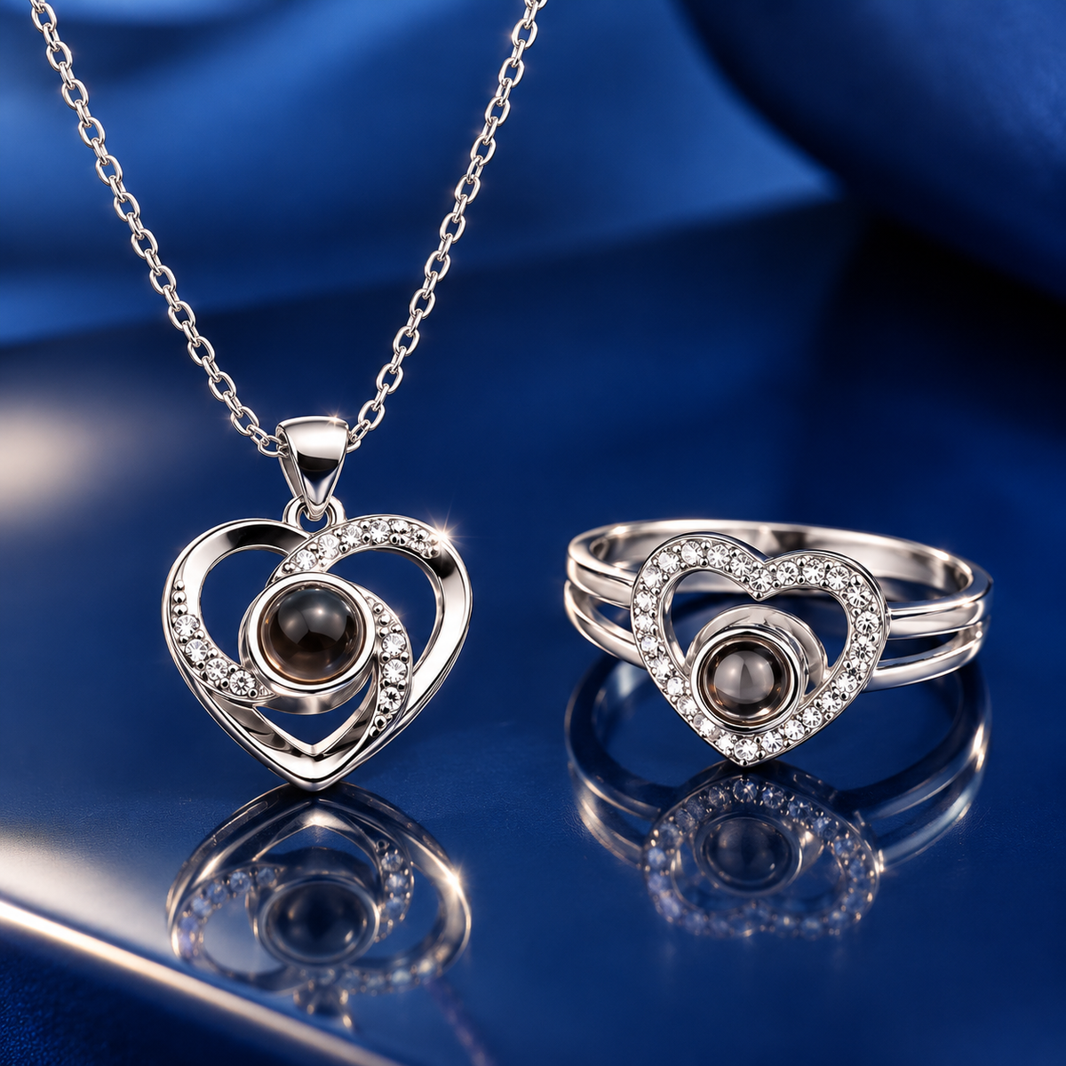Silbernes Herz-Schmuckset mit Kristallen: Fotokette mit Herzanhänger und Herzring auf dunkelblauem Satin