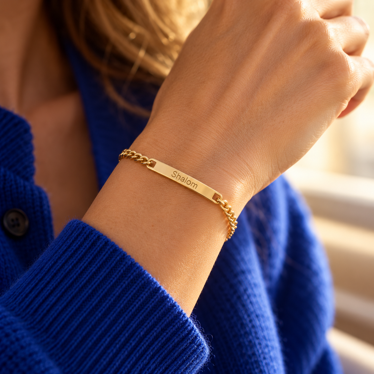 Armband mit Namensgravur am Handgelenk einer Frau – Gold, Gravur „Shalom“
