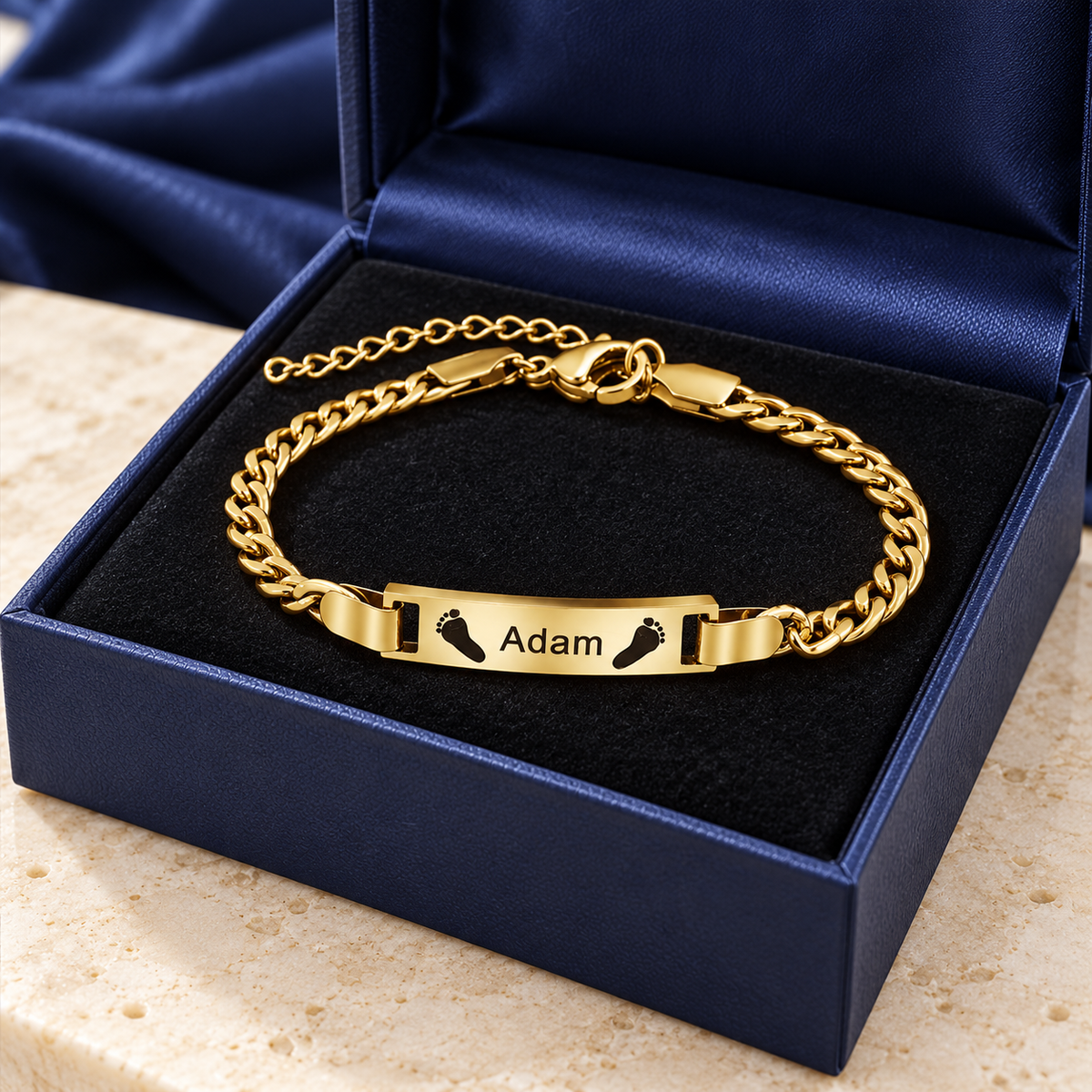 Goldenes Babyarmband mit Namensgravur und Füßchen in Geschenkbox