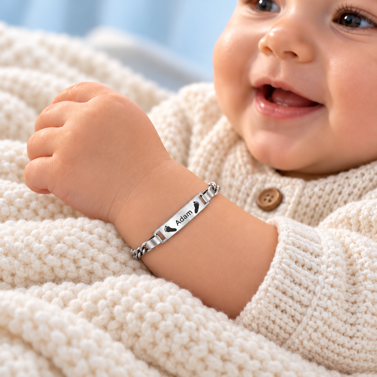 Baby trägt silbernes Babyarmband mit Gravur „Adam“ und Füßchen – Geschenk zur Geburt