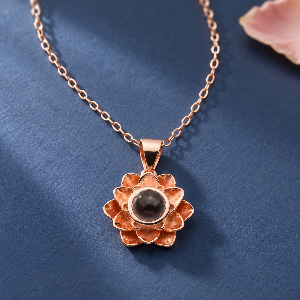 Roségoldfarbene Blumenkette von 4MyLove mit mehrlagigem Blütenanhänger und dunkler Fotolinse vor blauem Hintergrund