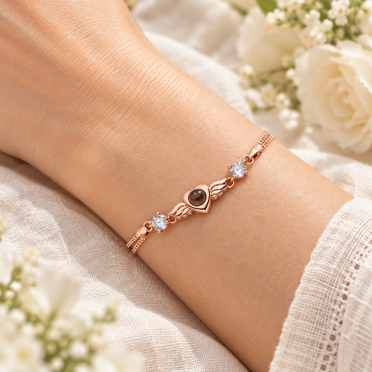 Roségoldfarbenes Flügelherz-Fotoarmband von 4MyLove mit Fotolinse und zwei klaren Schmucksteinen, am Handgelenk getragen